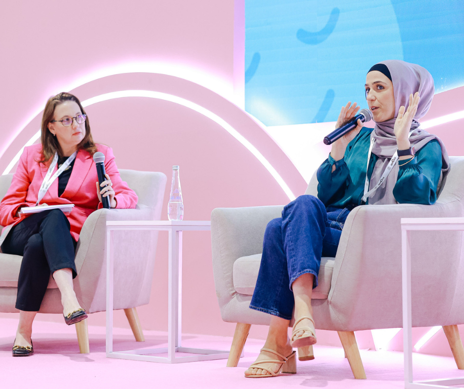 Two women sitting on the stage holding microphones.