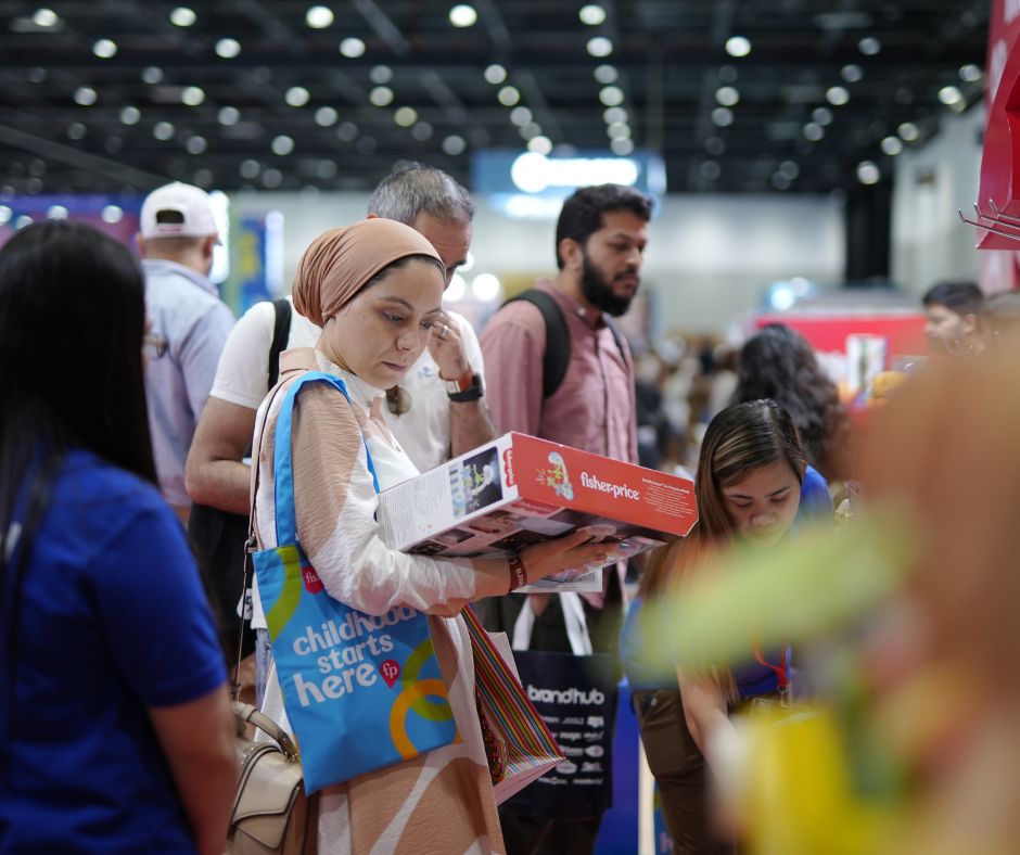 A woman at the Baby Expo Riyadh reading the back of a box containing a toy.