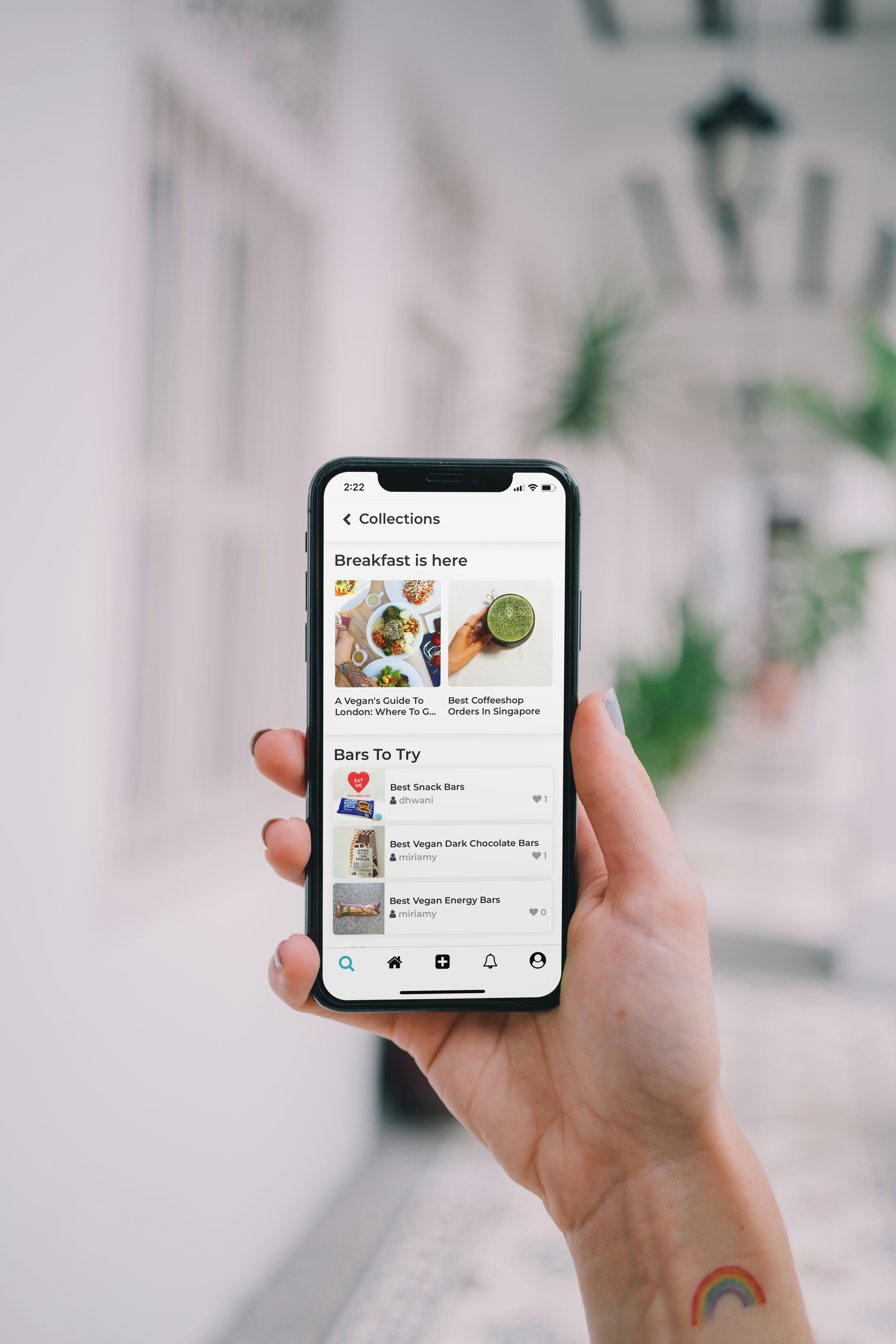 A hand holding an iPhone with a food delivery app displayed on the screen.